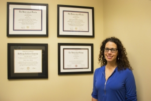 Jessie standing in front of a wall of degrees